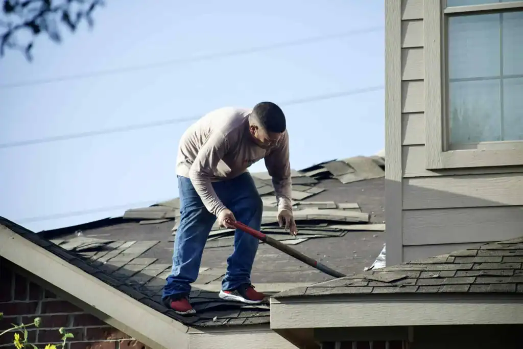 Roofer removing damaged shingles during a residential roof replacement – Roof Repair Westchester.