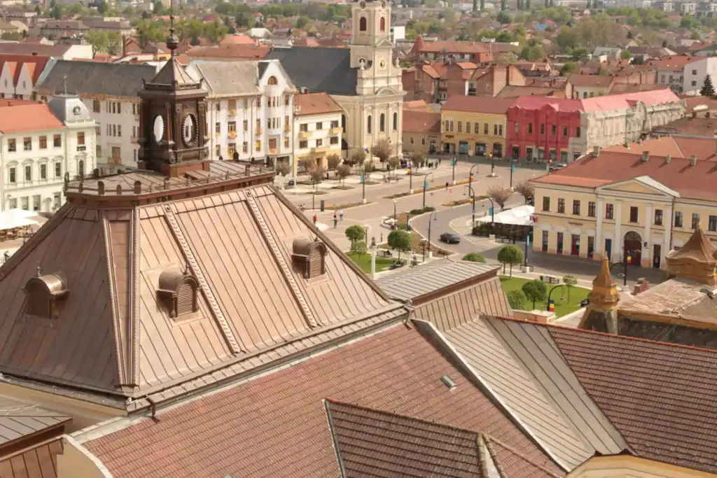 Historic European town square with colorful buildings and a copper-roofed clock tower under a clear sky.